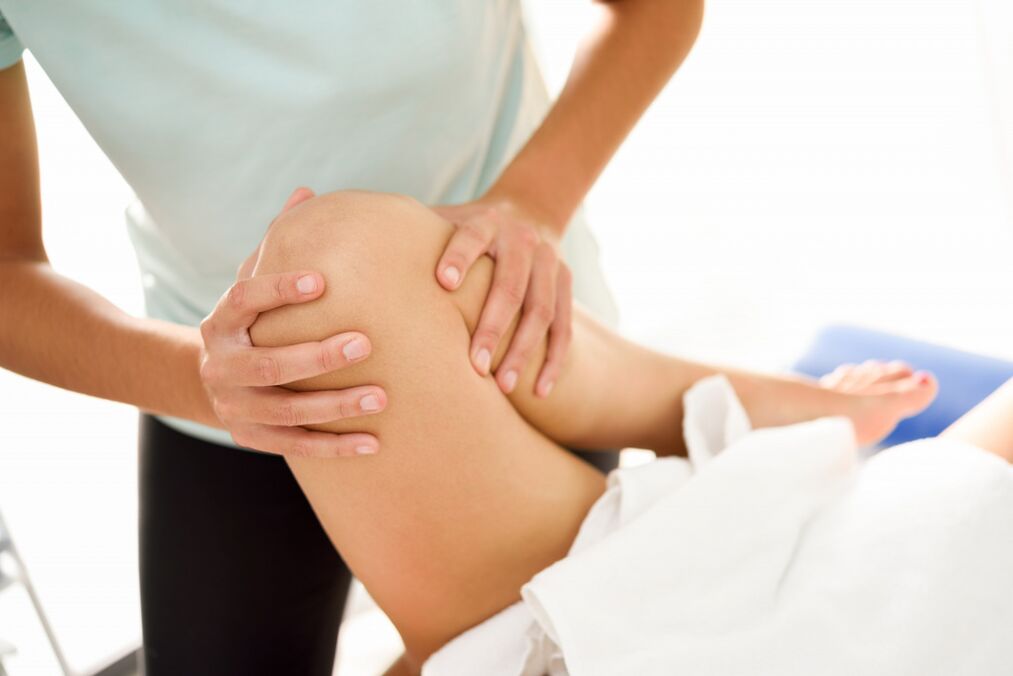 The specialist does therapeutic massage with knee arthrosis